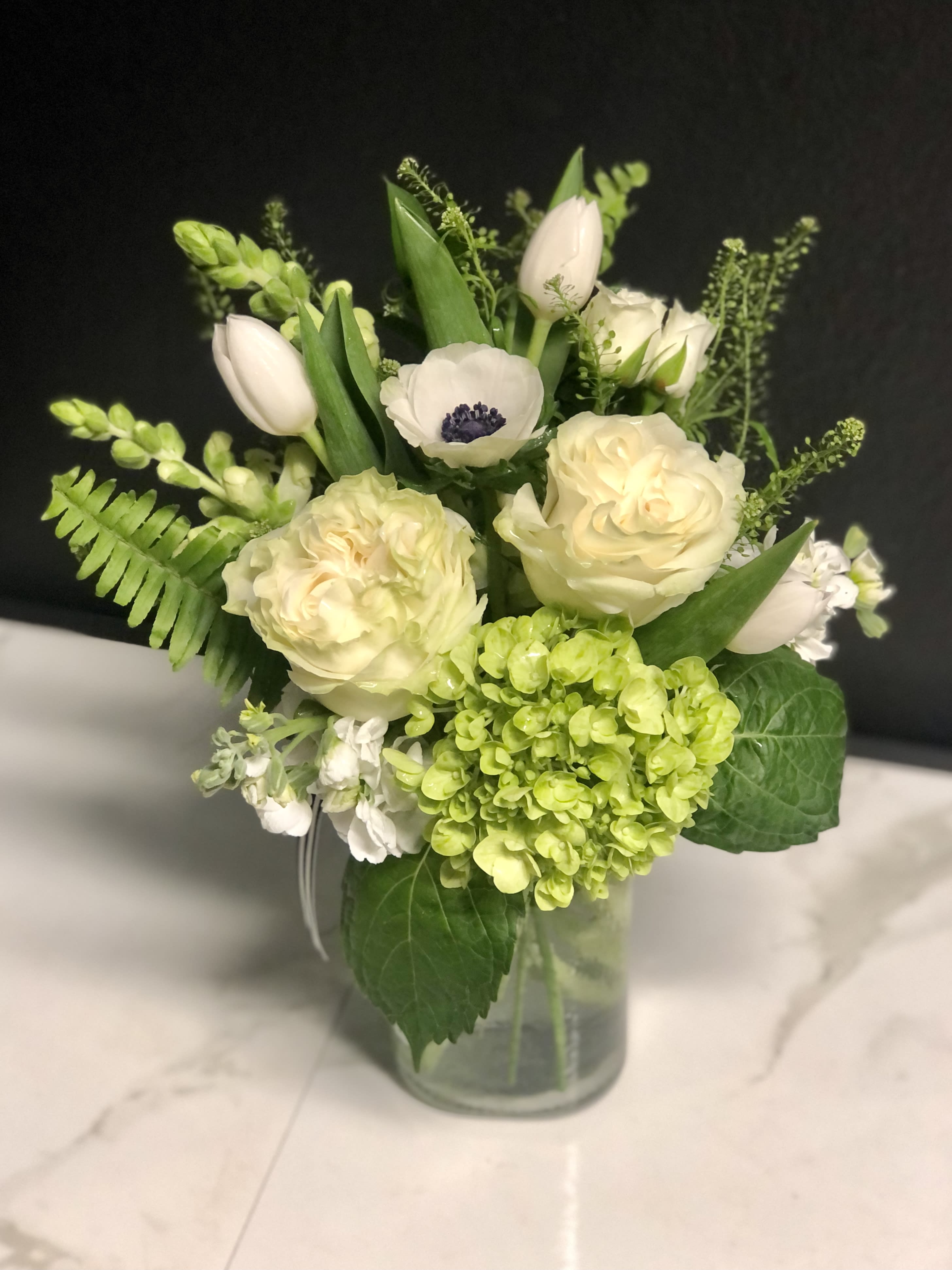 White and pale green floral arrangement in a glass vase