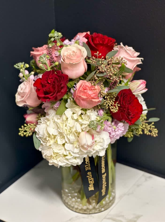 Bouquet of pink and red roses with white hydrangea in a glass vase