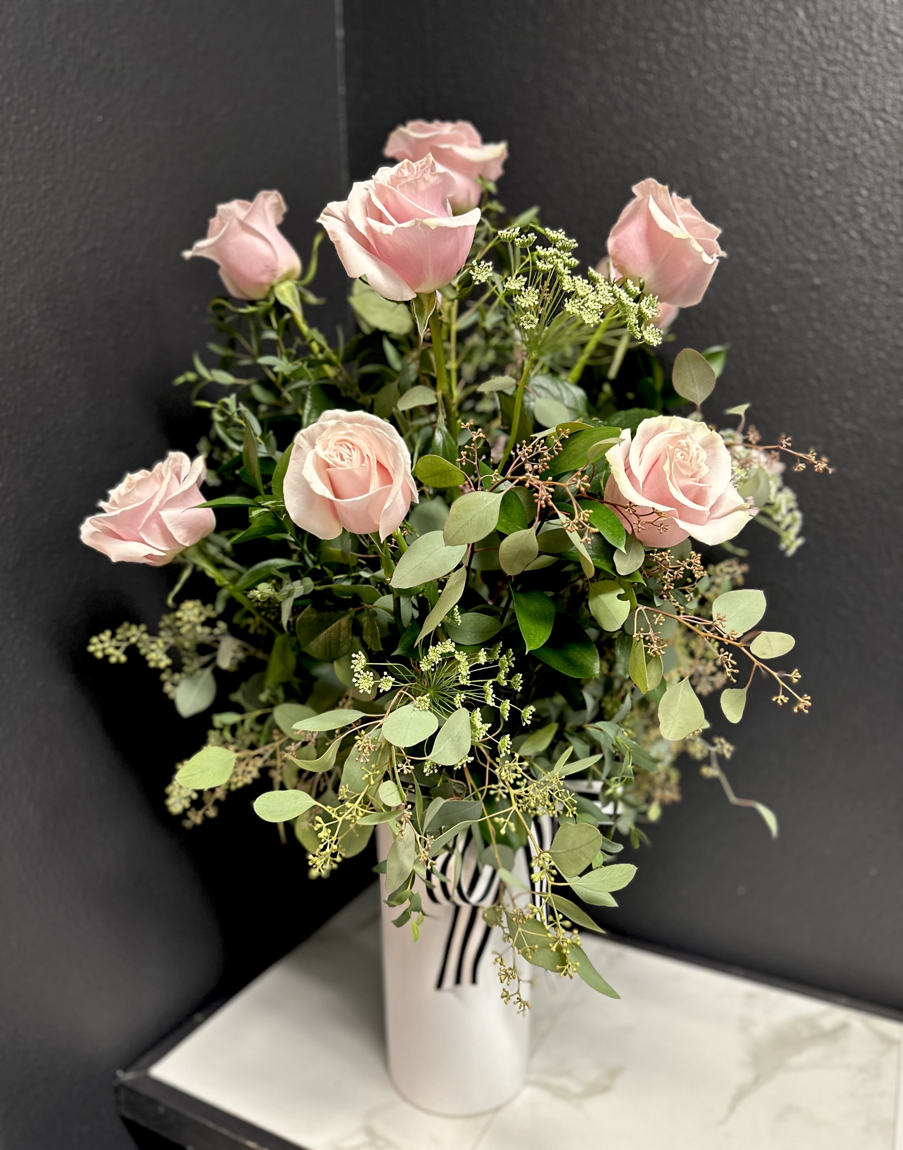 Pink roses in a white vase with airy greenery
