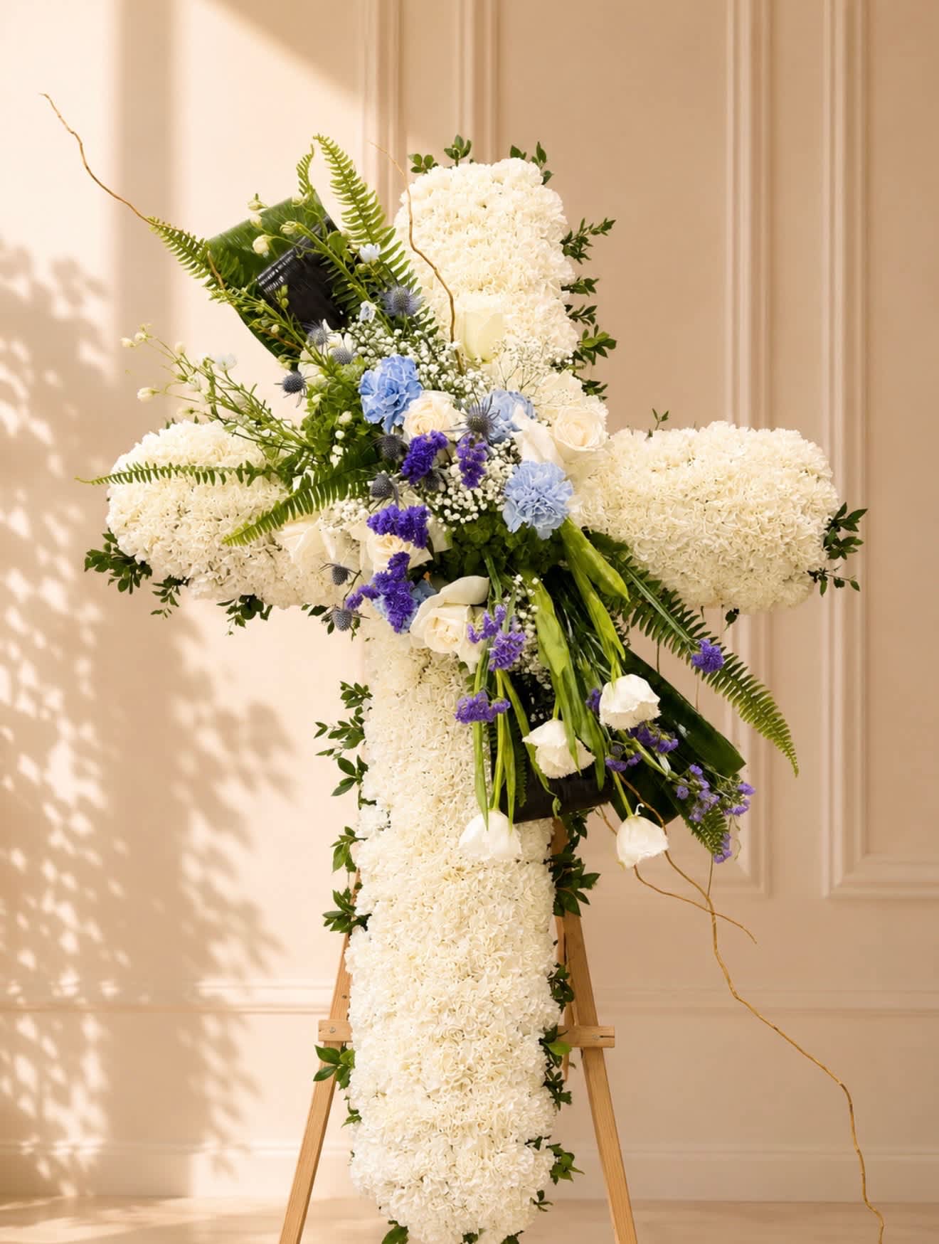 Large white floral cross on an easel with blue and purple accents