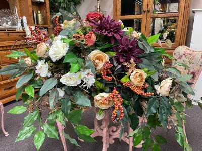 Large floral arrangement with roses, white blooms, and purple flowers in a stand
