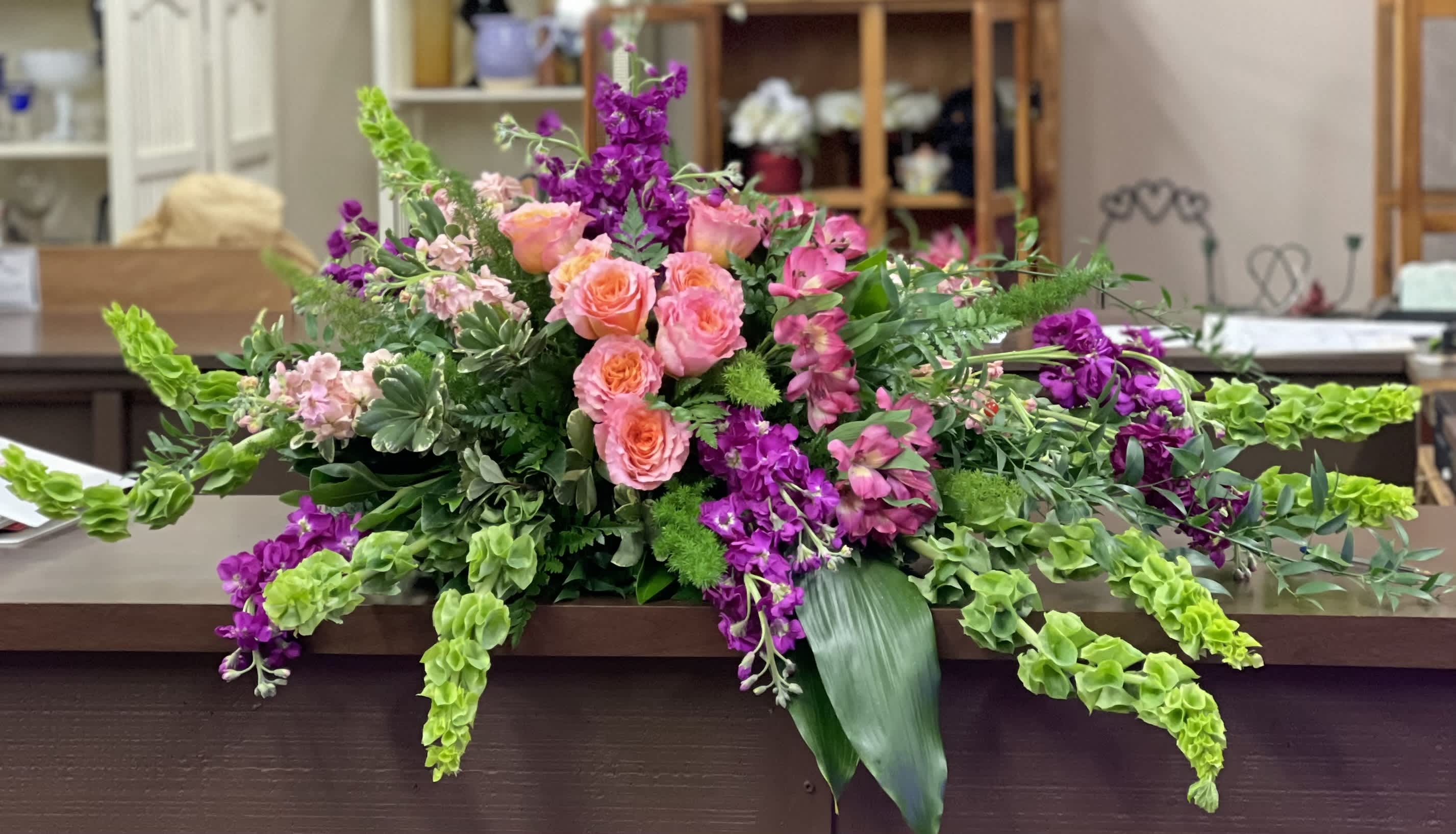 Large floral arrangement with pink roses and purple flowers on a table