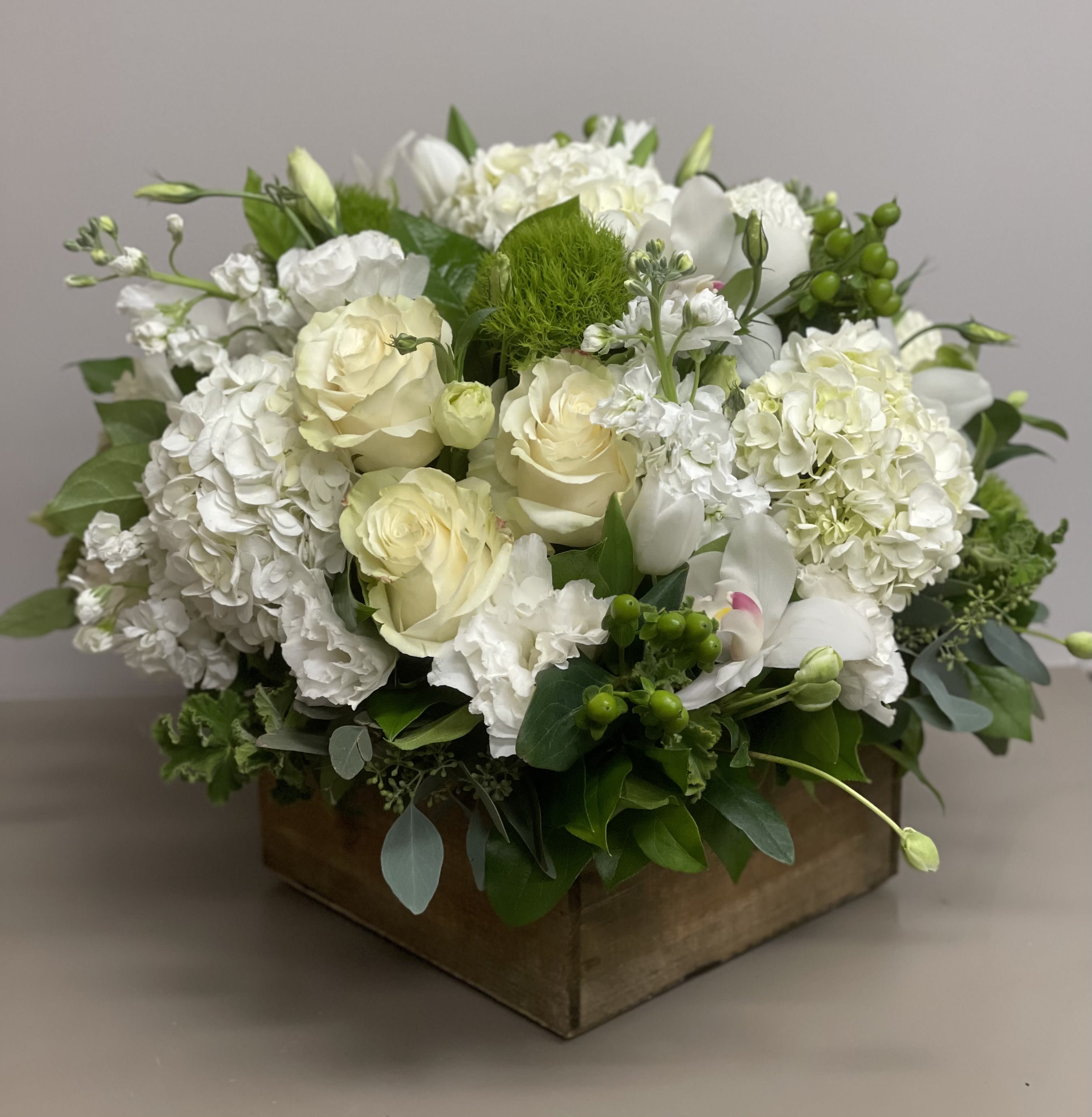 Low white and cream flower arrangement with roses and hydrangeas in a wooden box