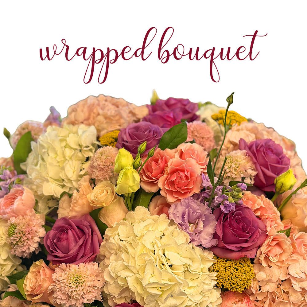 Wrapped bouquet of pink and peach blooms with purple roses and ivory hydrangeas
