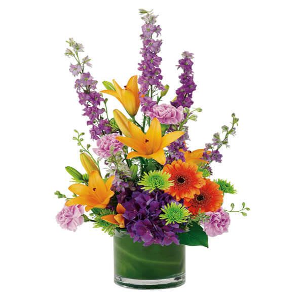 Colorful bouquet with lilies, gerbera daisies, and purple blooms in a glass vase