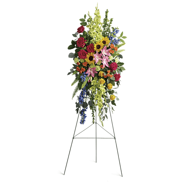 Standing floral spray with roses, lilies, sunflowers, and blue accents on an easel
