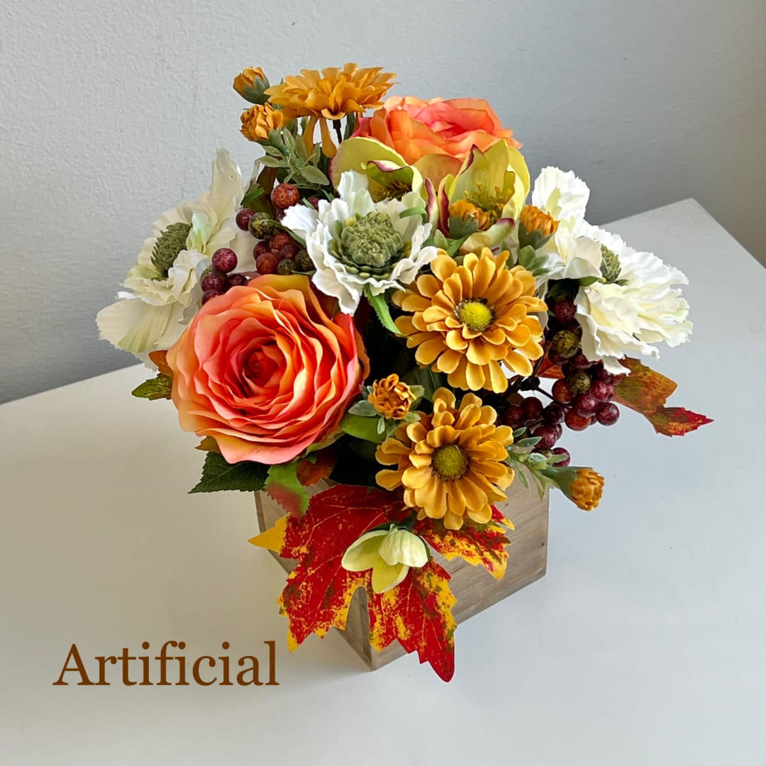 Artificial bouquet of orange, yellow, and white flowers in a wooden box