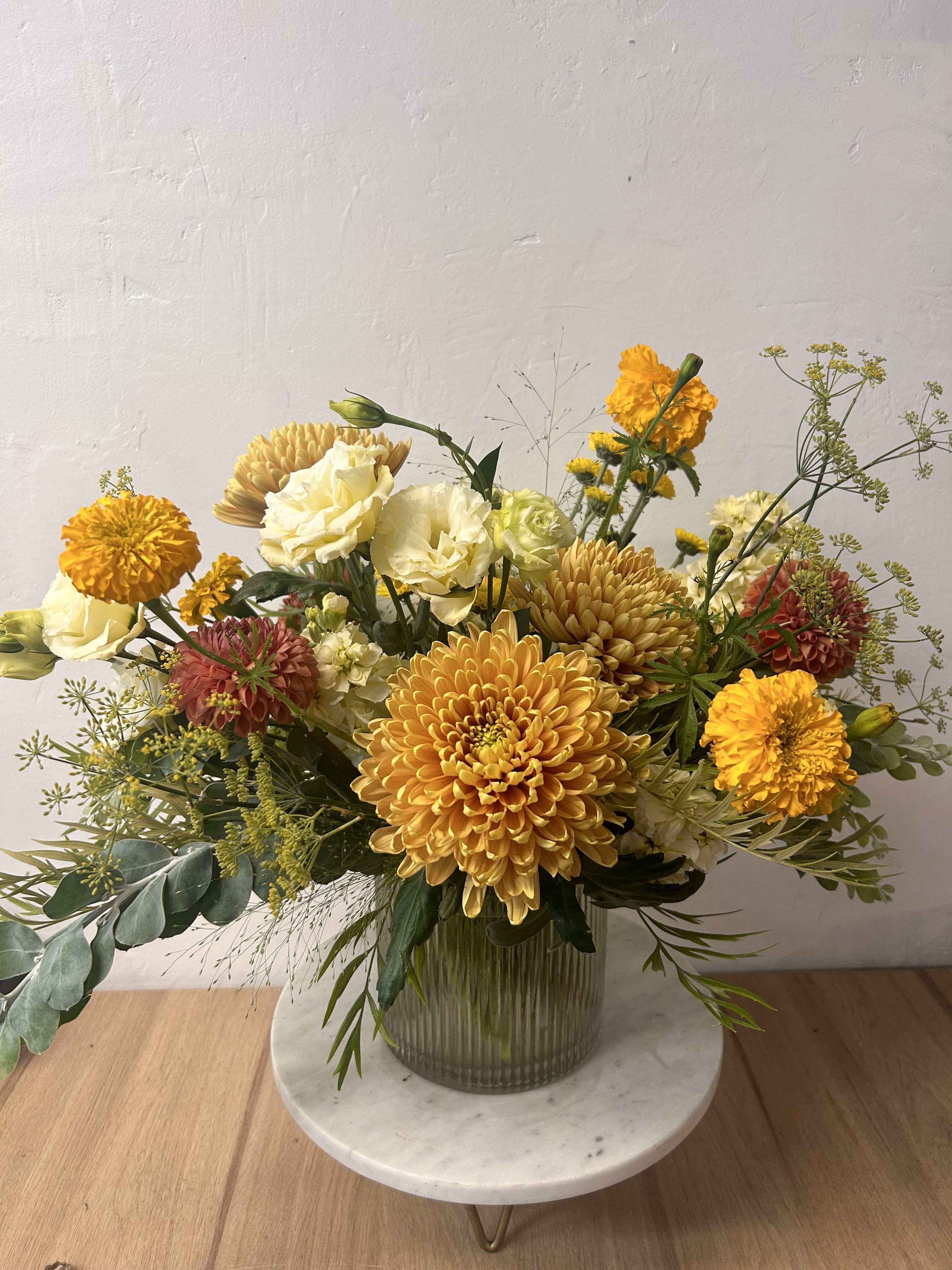 Mixed yellow and cream flowers arranged in a glass vase
