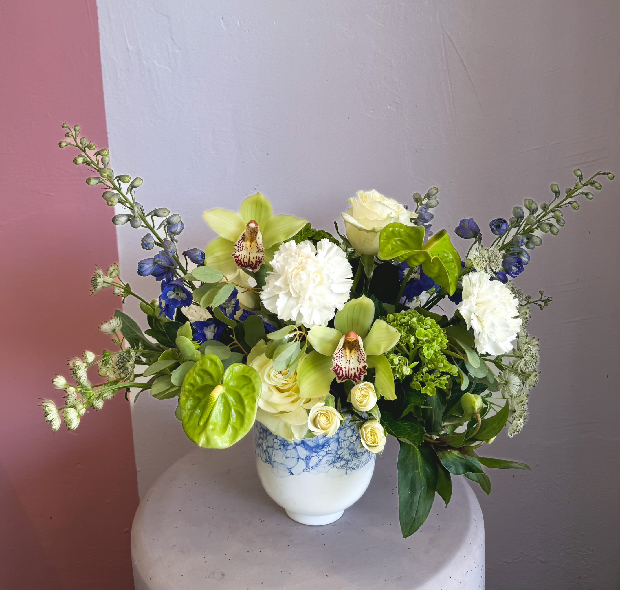 Mixed bouquet in a white vase with pale green orchids and white blooms