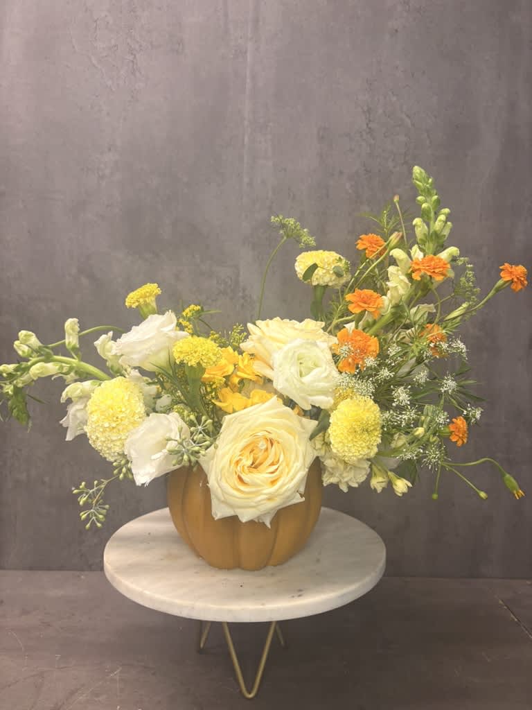 Yellow and white floral arrangement in a pumpkin-shaped vase