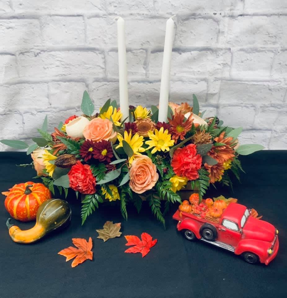 Autumn floral centerpiece with two white taper candles and pumpkins