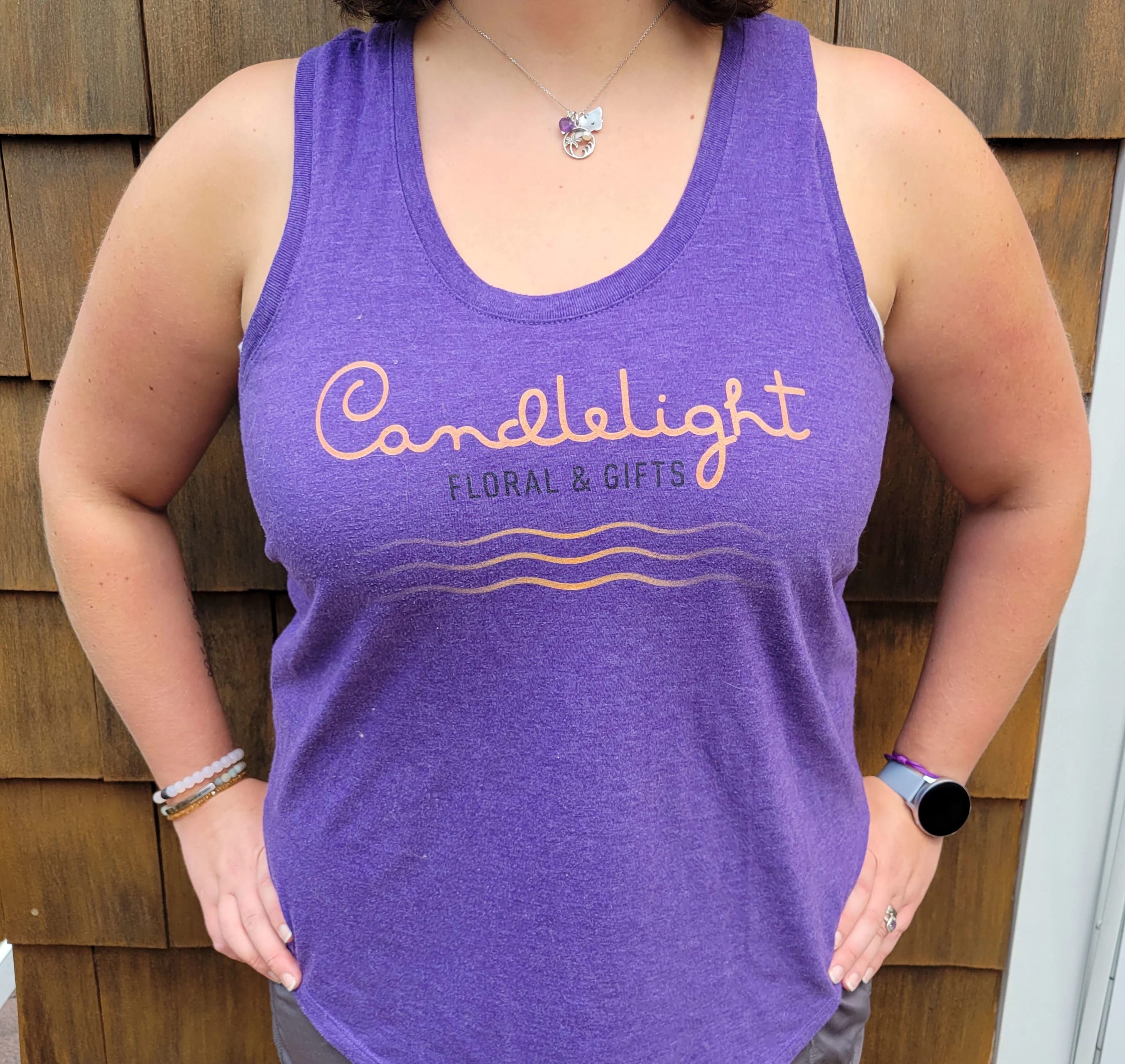 Person wearing a purple tank top with a floral shop logo