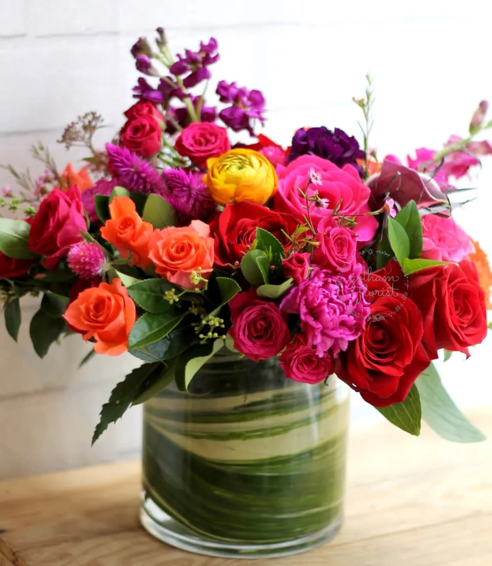 Mixed bouquet of roses and bright flowers in a glass vase