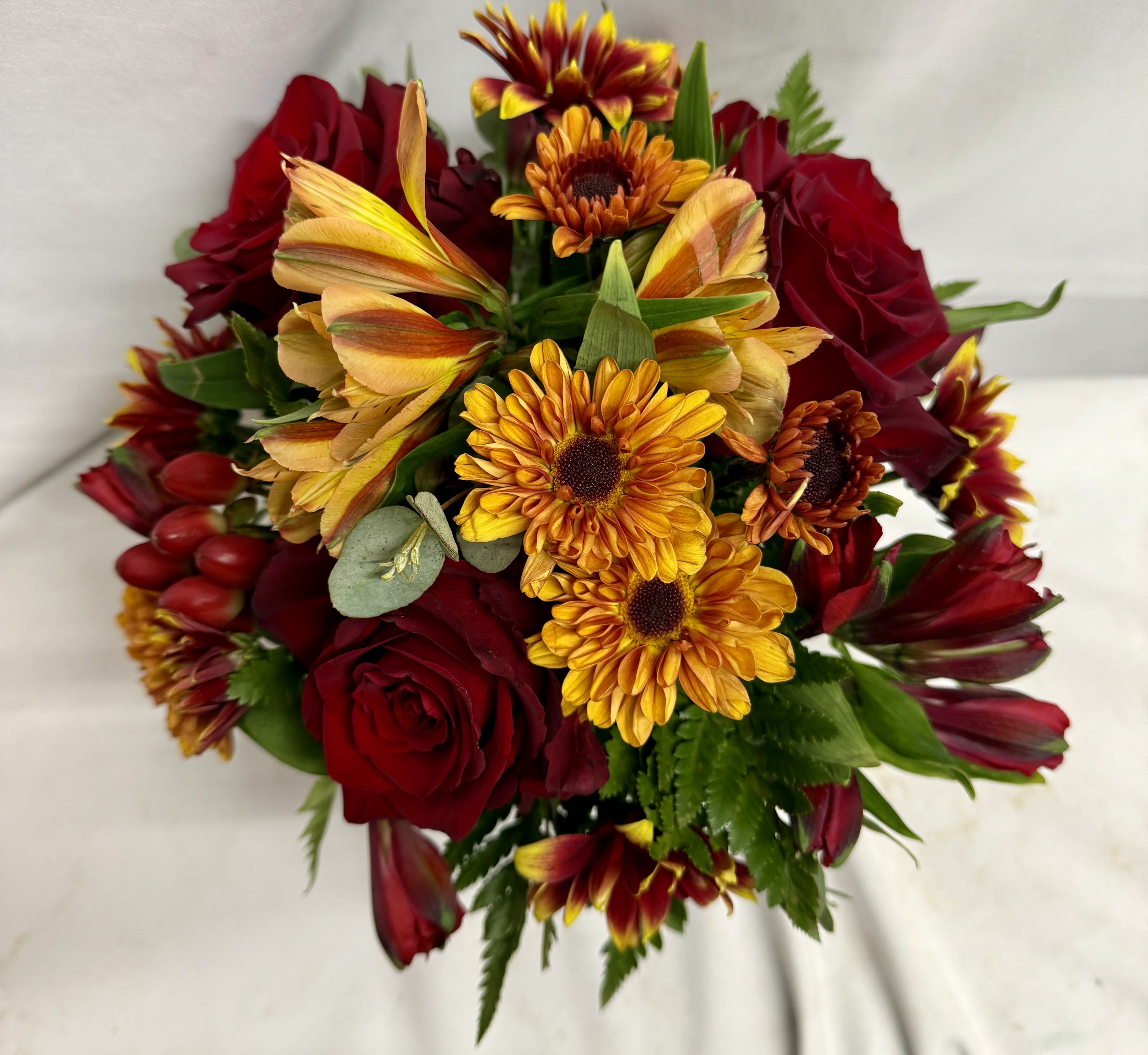 Bouquet of red roses and yellow-orange daisies on a white background