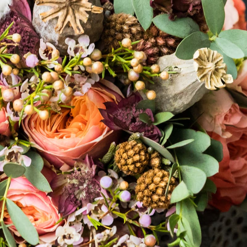 Close-up bouquet with peach roses, purple accents, and eucalyptus