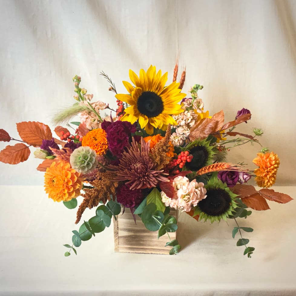 Autumn floral arrangement with sunflowers, chrysanthemums, and a wooden box