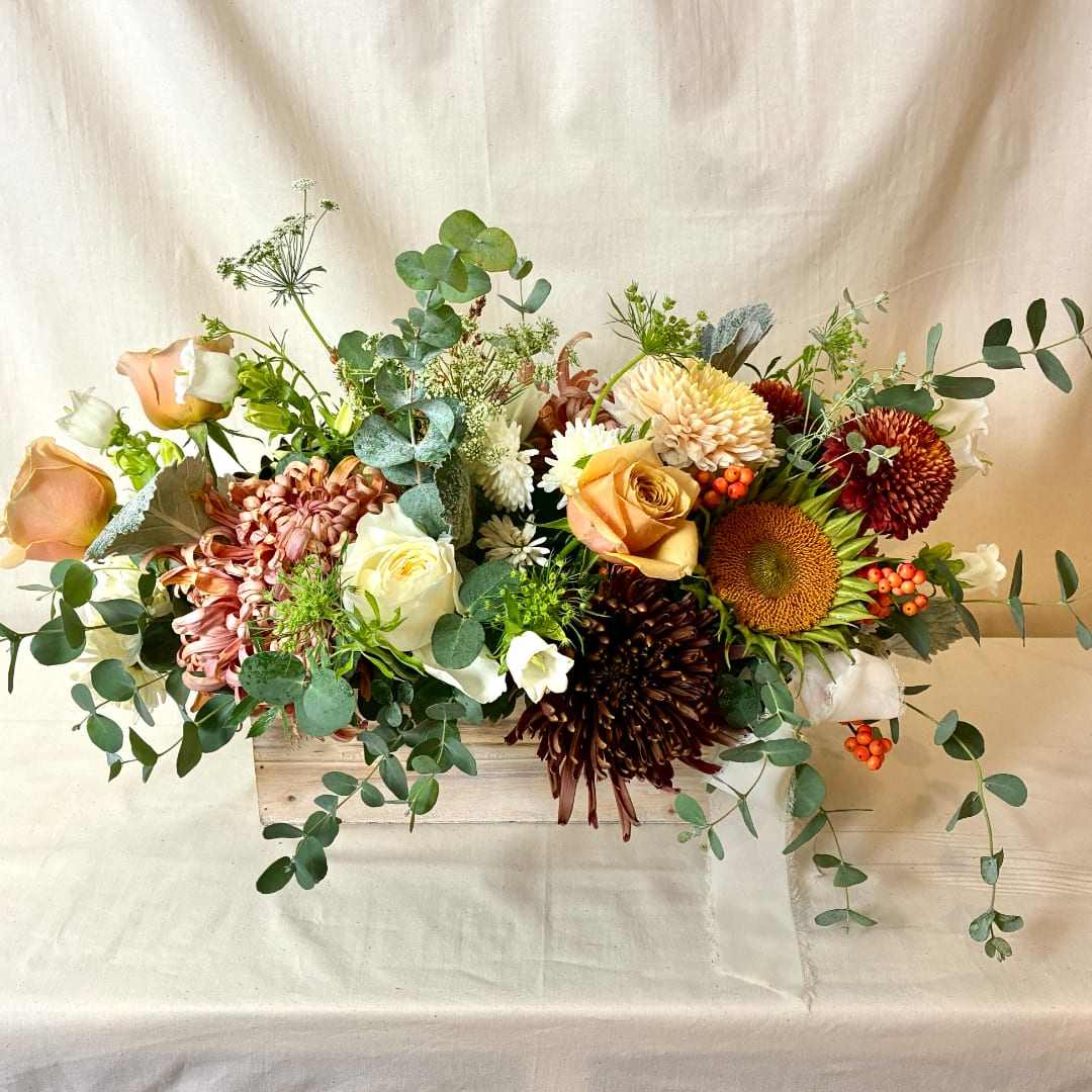 Mixed bouquet in a wooden box with roses, chrysanthemums, and sunflowers