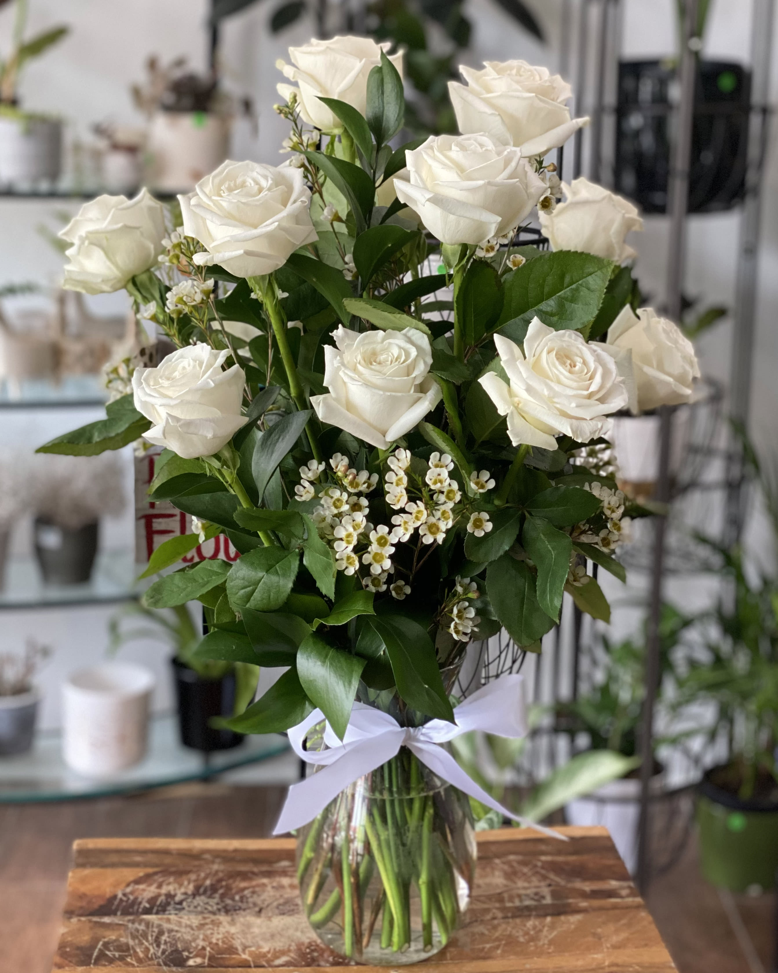 Bouquet of white roses in a clear glass vase with a white ribbon