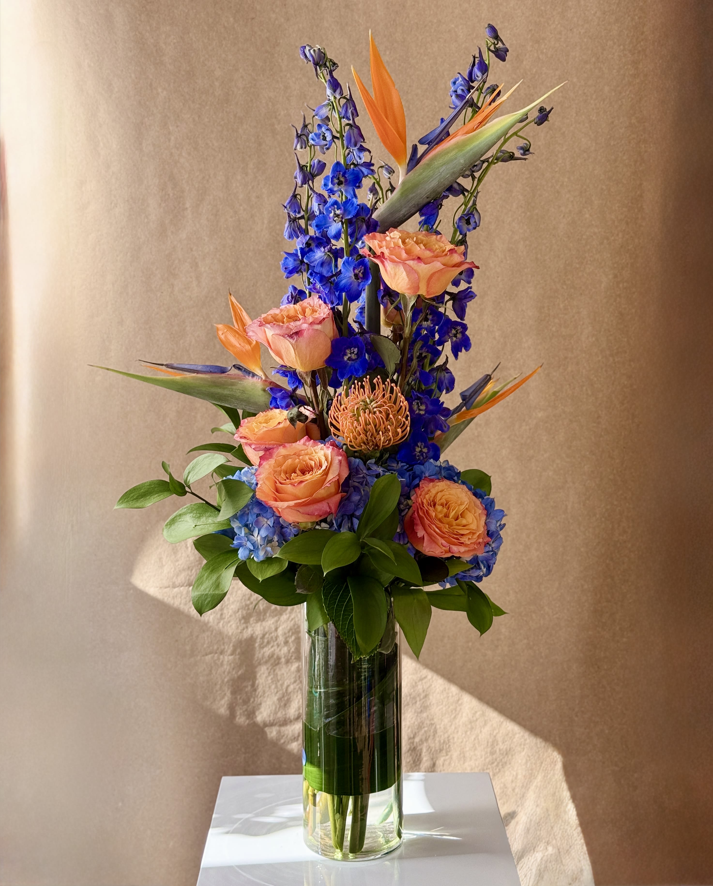 Tall bouquet of orange and pink flowers in a clear glass vase