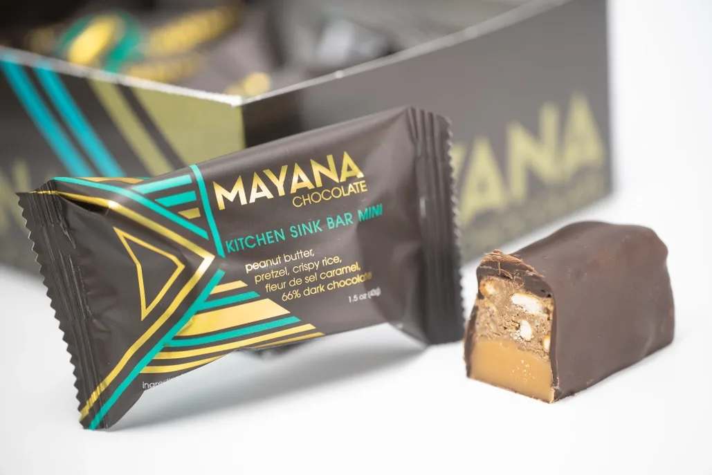 Wrapped chocolate bar with a cut piece showing caramel and nuts
