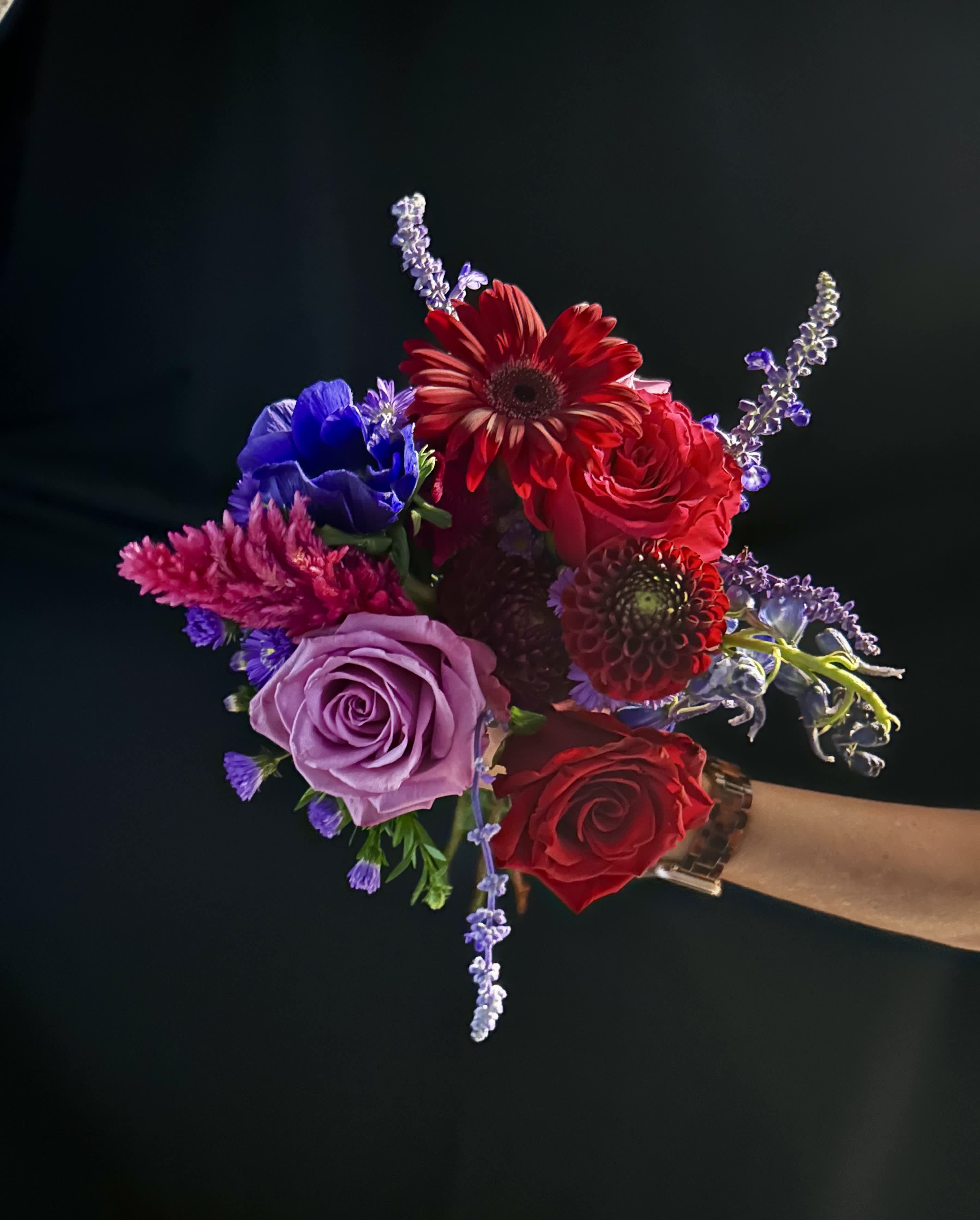 Handheld bouquet with red, lavender, and blue flowers