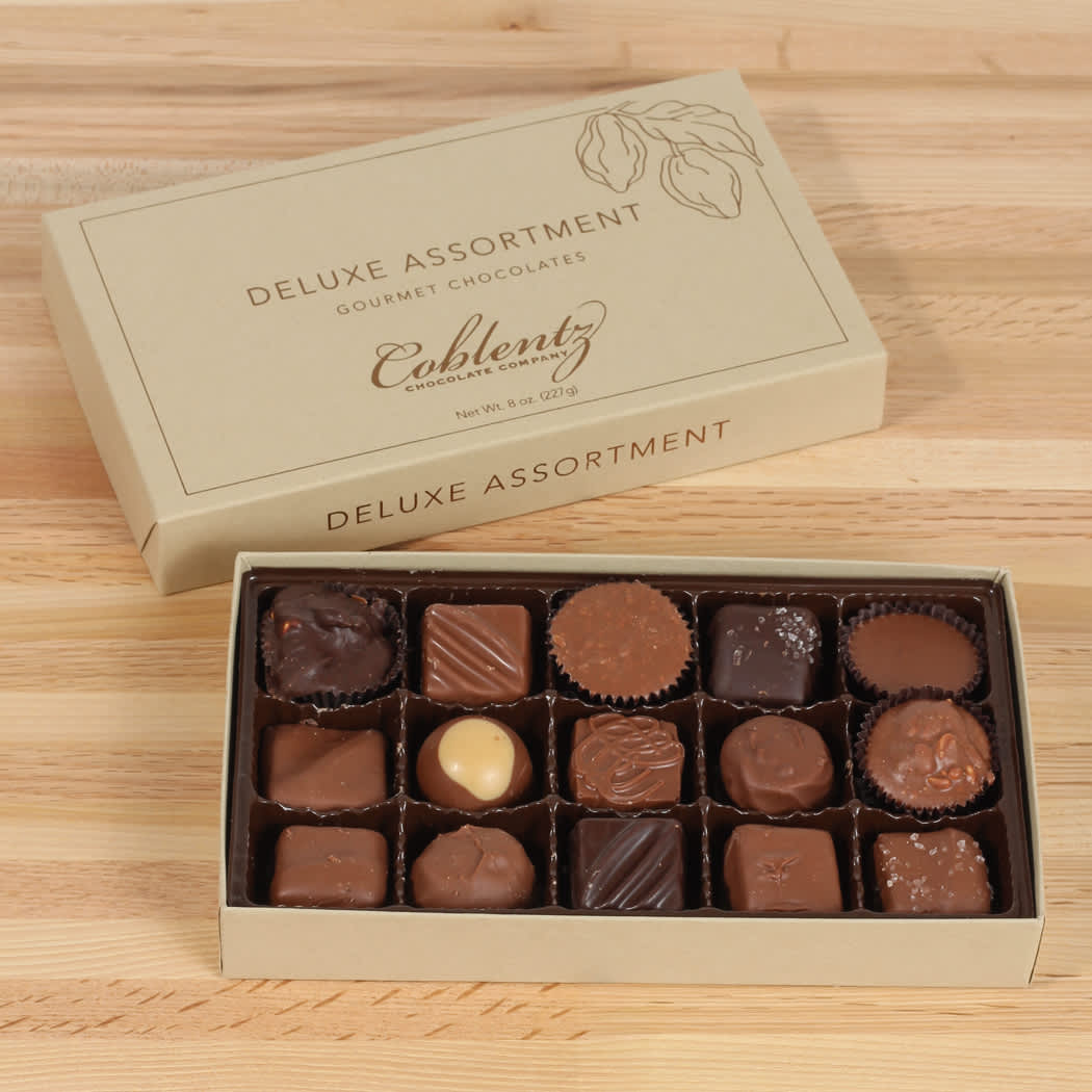 Box of assorted chocolates with the lid beside it on a wooden surface
