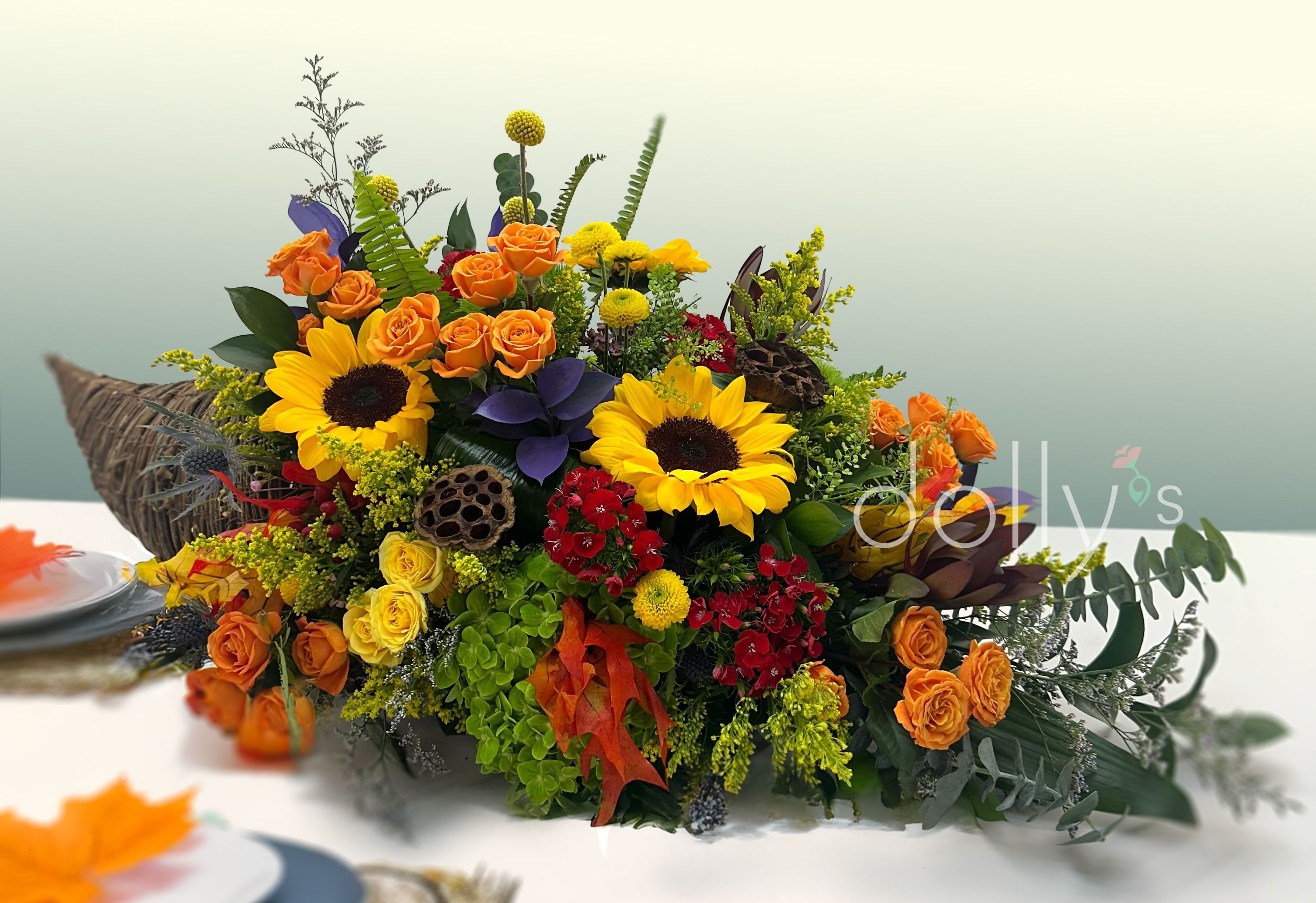 Colorful floral arrangement with sunflowers and orange roses in a low container