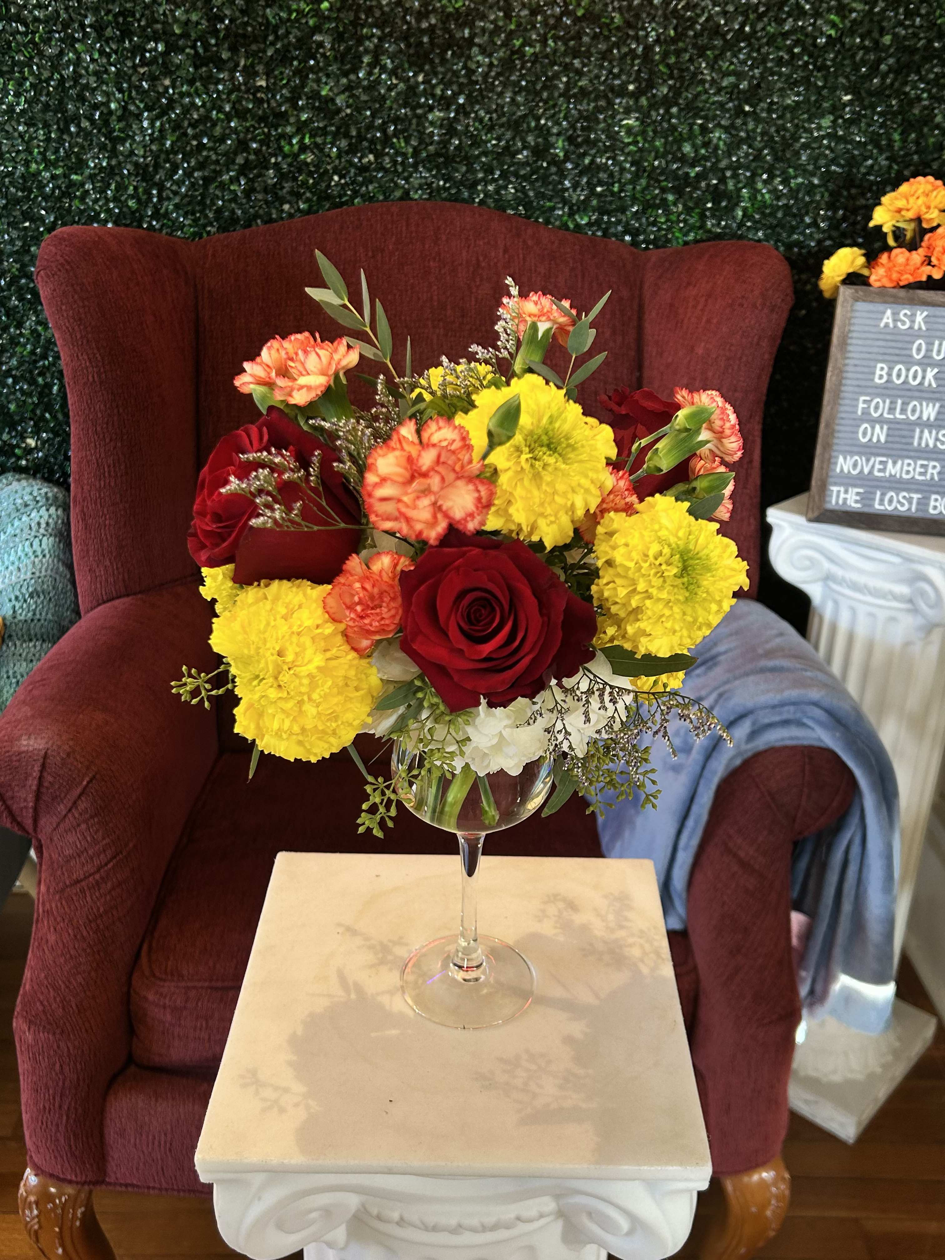 Red roses and yellow carnations in a wine glass vase