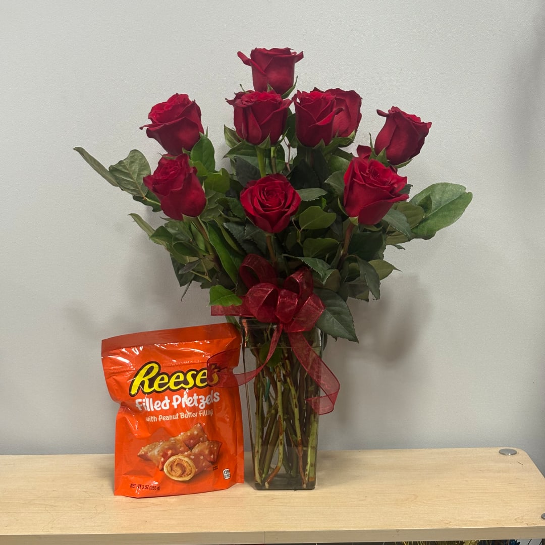 Red roses in a glass vase with a ribbon, beside a Reese's pretzel bag