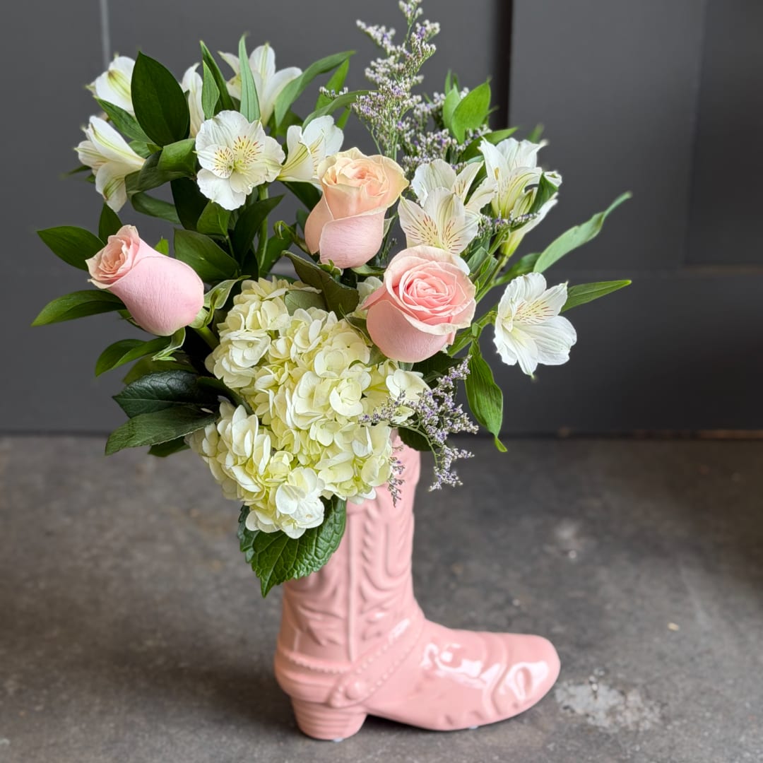Pink roses and white flowers arranged in a pink boot vase