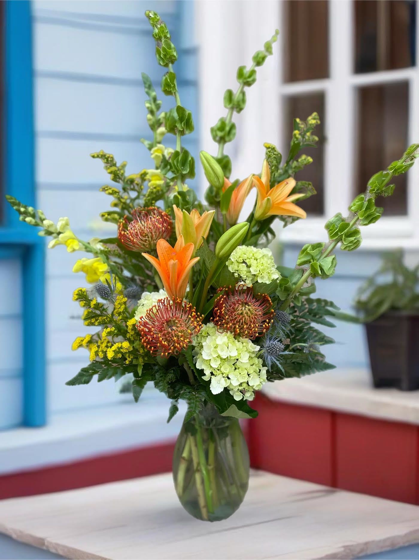 Mixed bouquet with orange lilies and green hydrangeas in a glass vase