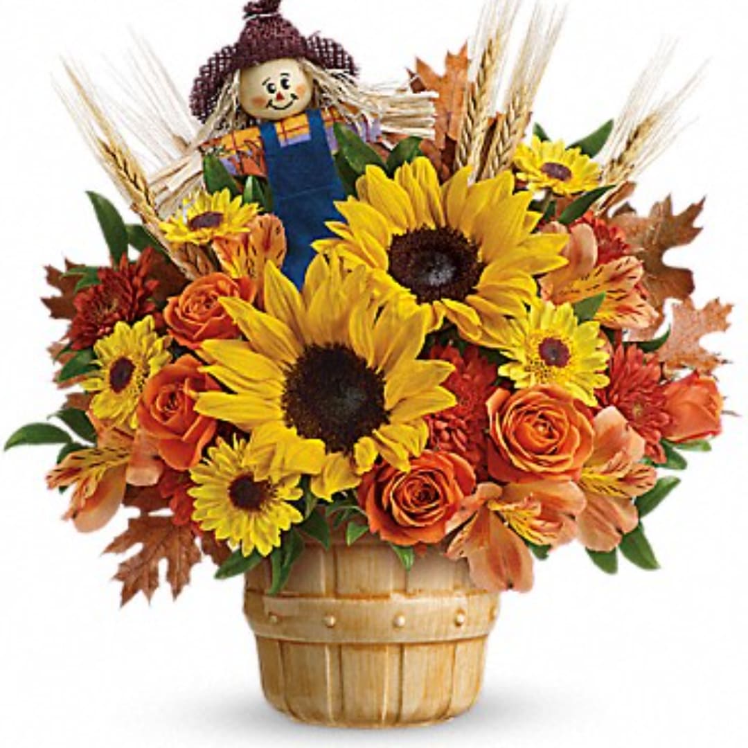 Sunflower and rose arrangement in a basket with a scarecrow topper