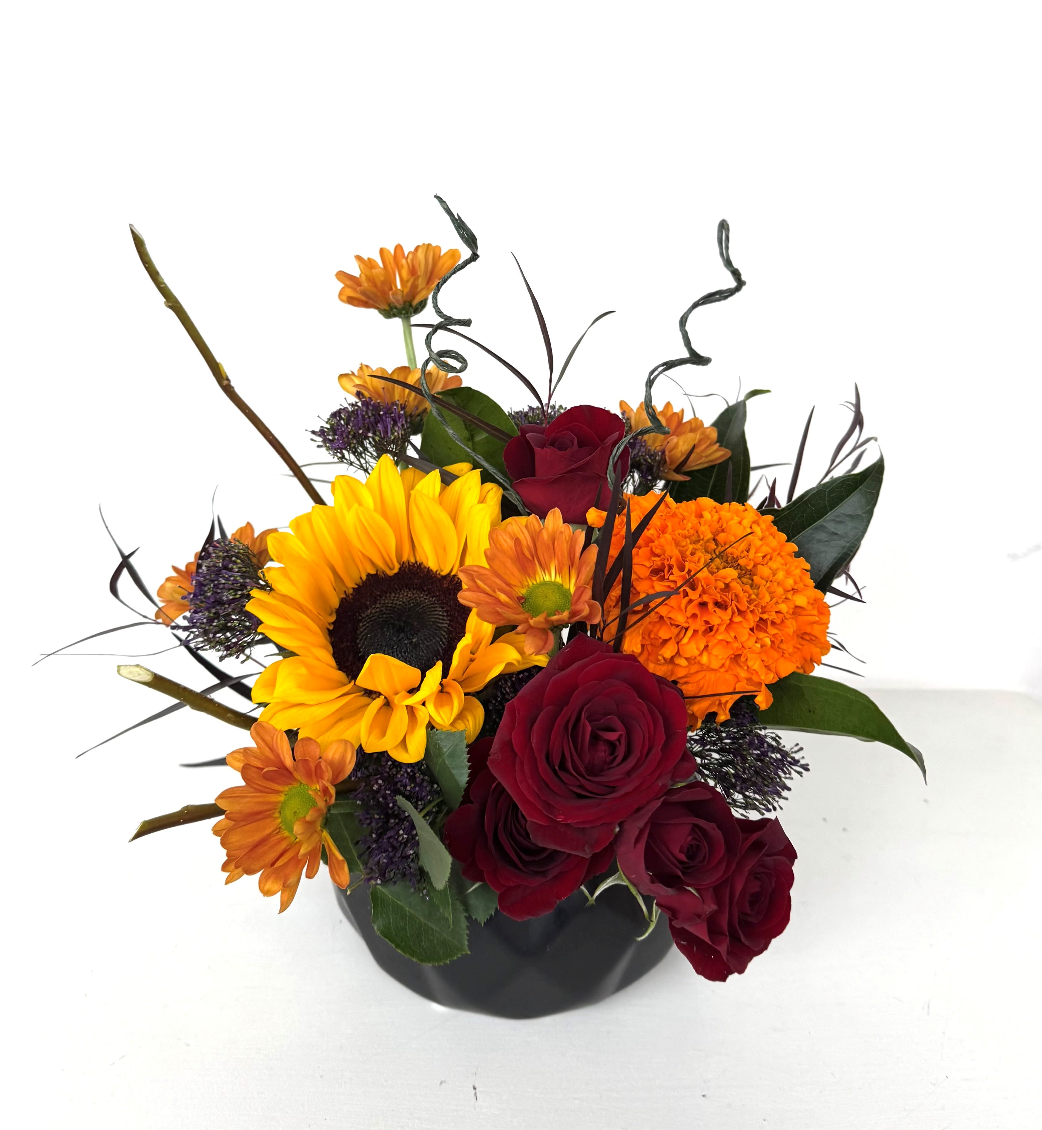Bouquet of sunflowers, red roses, and orange mums in a black vase