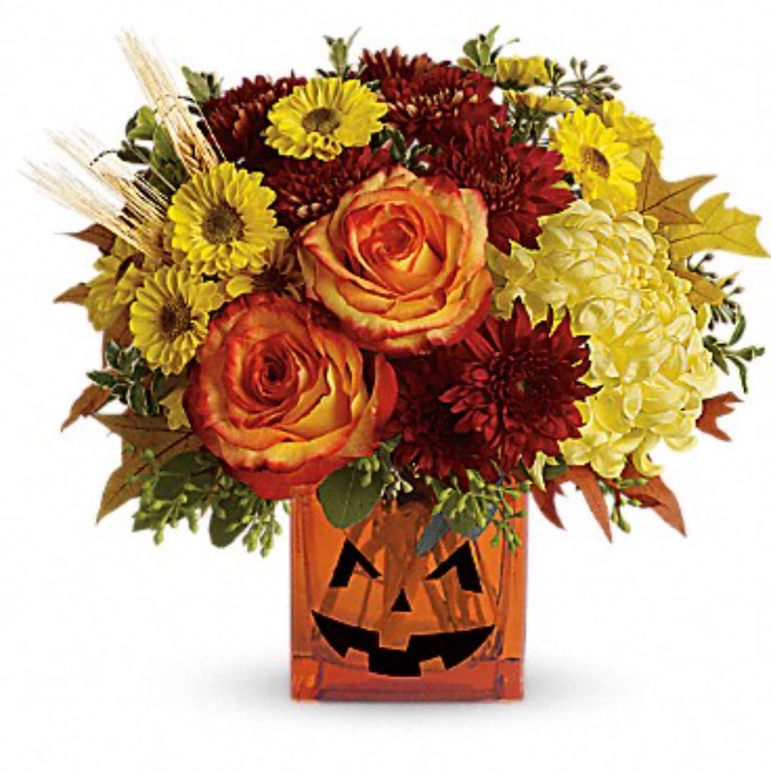 Autumn bouquet of orange roses and yellow mums in a jack-o'-lantern vase