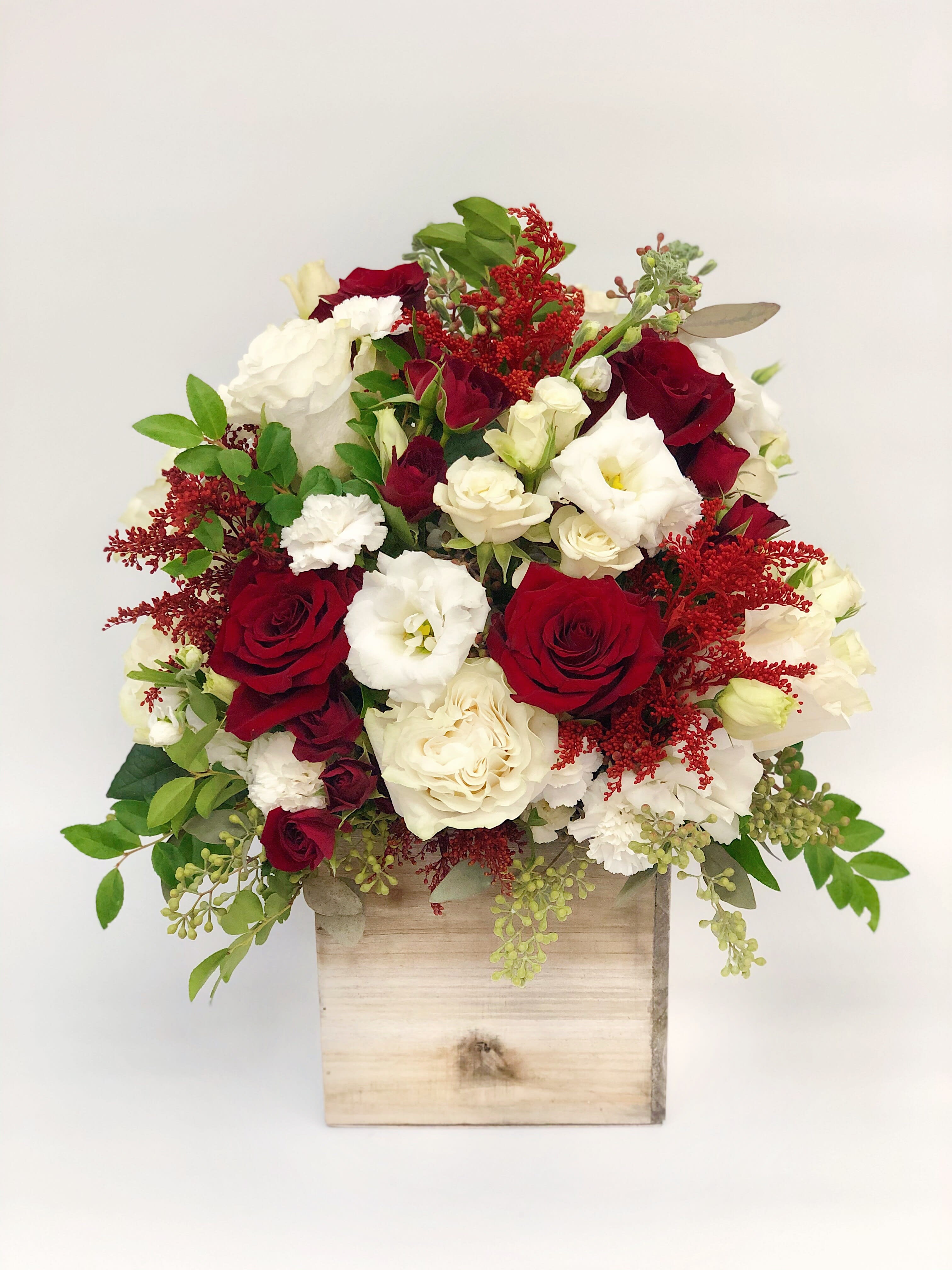 Red and white rose arrangement in a wooden box
