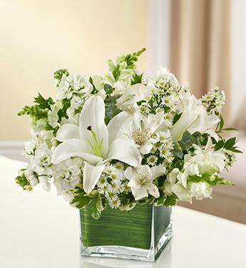 In my Thoughts - All White - Product ID: 95378  Elegant white flowers help to convey your deepest sympathies with graceful beauty that heals the soul. Our lovely cube vase arrangement offers a lasting tribute to friends and family members, crafted from fresh roses, lilies, snapdragons, monte casino and more. Elegant, all-white arrangement of roses, lilies, snapdragons, monte casino, stock and alstroemeria, accented with variegated pittosporum, myrtle and spiral eucalyptus Artistically designed by our florists in a classic clear glass cube vase lined with a Ti leaf ribbon; vase measures 5"H x 5"D Appropriate for the service or for sending to the home or office of friends and family members Large arrangement measures approximately 11"H x 11"L Medium arrangement measures approximately 10"H x 10"L Small arrangement does not include roses and measures approximately 9"H x 9"L Our florists hand-design each arrangement, so colors, varieties, and container may vary due to local availability Lilies may arrive in bud form and will open to full beauty over the next 2-3 days