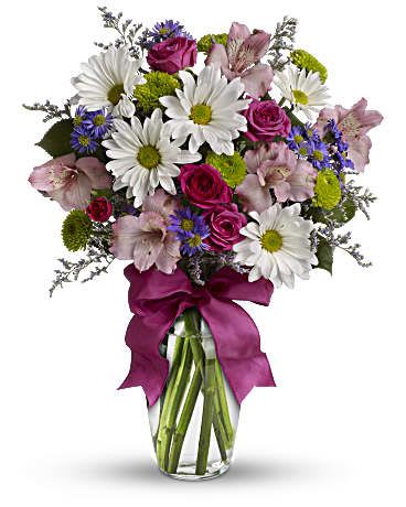 Mixed bouquet of daisies, roses, and alstroemeria in a glass vase with a ribbon