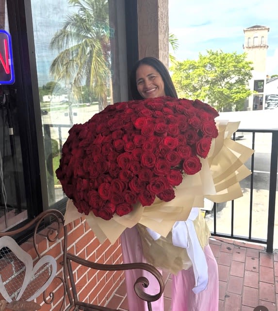 Woman holding a large bouquet of red roses wrapped in cream paper