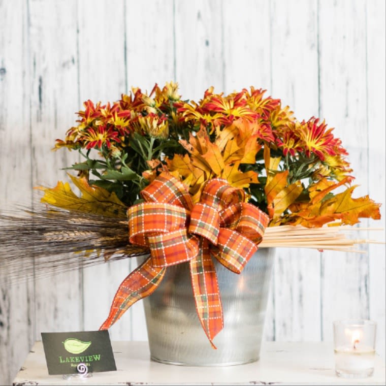 Fall bouquet of orange and yellow flowers in a metal bucket with plaid ribbon
