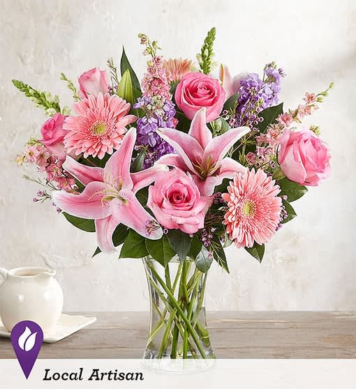 Pink roses, lilies, and gerbera daisies in a clear glass vase