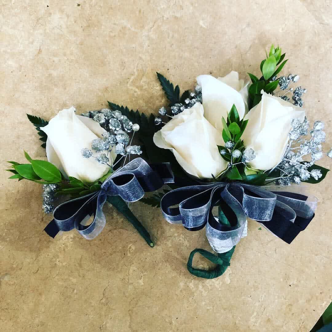 Pair of white rose boutonnieres with silver baby's breath and dark ribbon bows