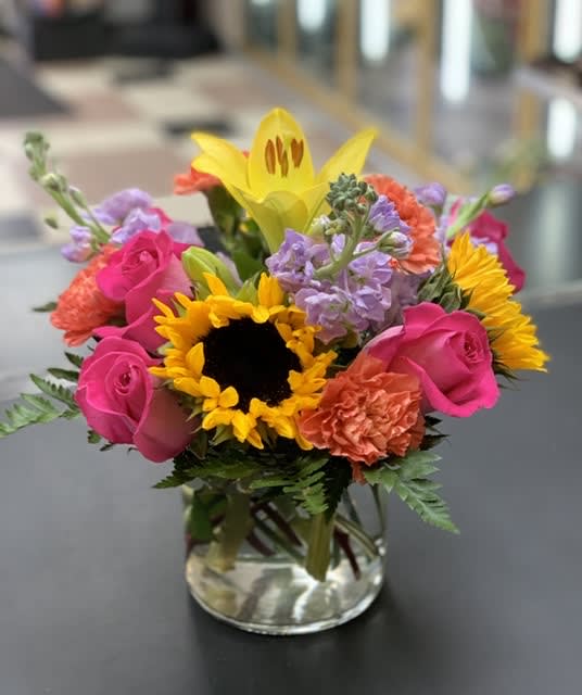 Bright mixed bouquet in a clear glass vase with sunflowers and pink roses