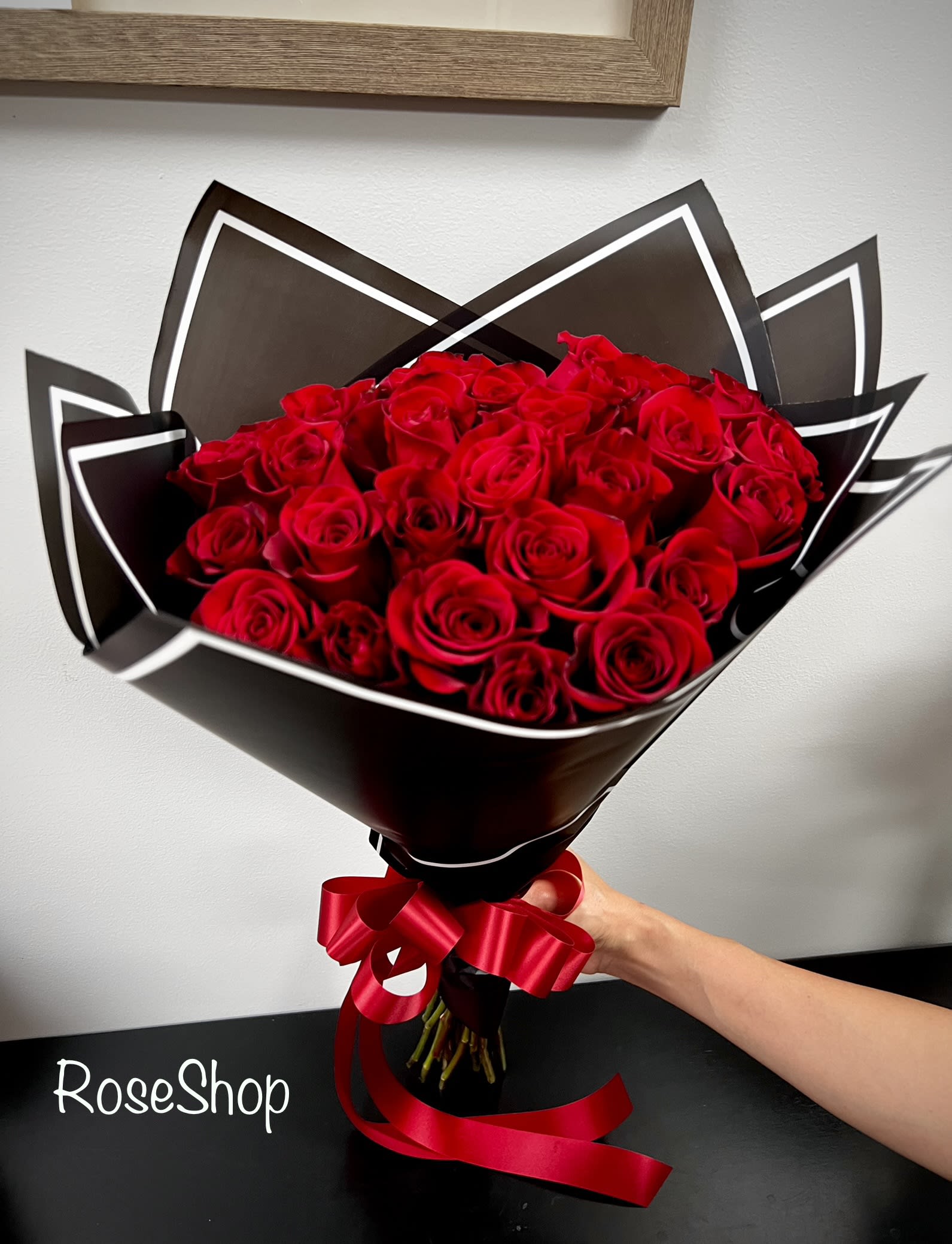 Bouquet of red roses wrapped in black paper with a red ribbon