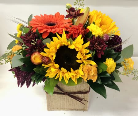 Burlap &amp; Blooms - Cheerful sunflowers arranged with fresh fall blooms and mixed greenery into square glass vase decorated with a burlap sleeve.