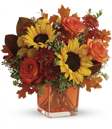 Hello Autumn - Vibrant autumn blooms arranged with fall leaves and mixed greenery into a glass vase.