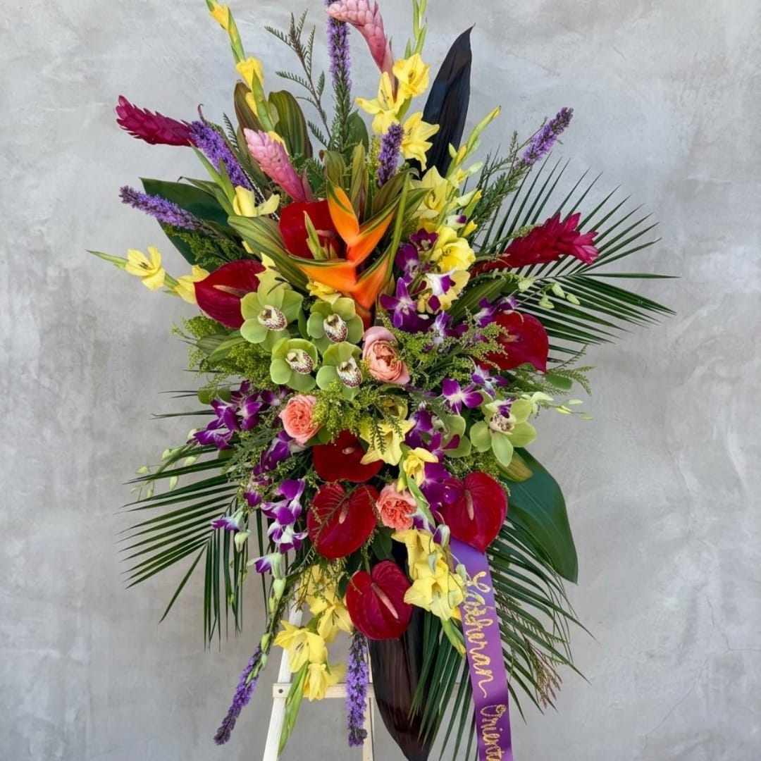 Tall tropical flower arrangement with orchids, anthuriums, and bright mixed blooms