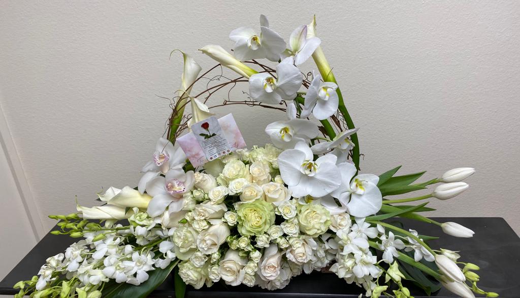 White orchid and rose floral arrangement in a woven basket