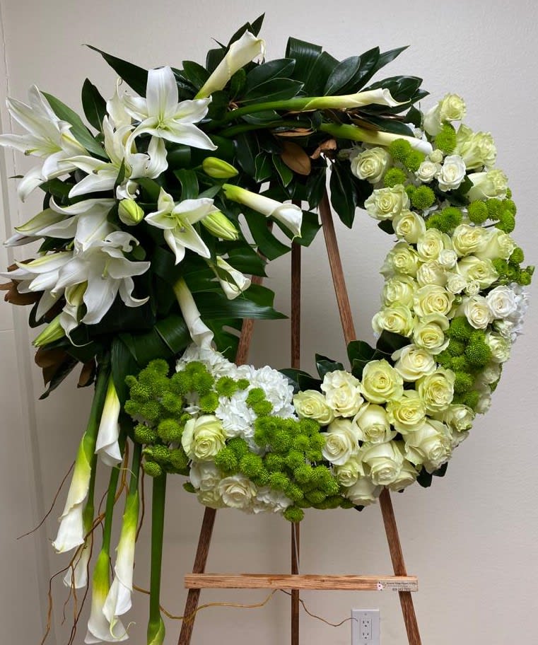 Floral wreath with white lilies, cream roses, and green pom-pom blooms