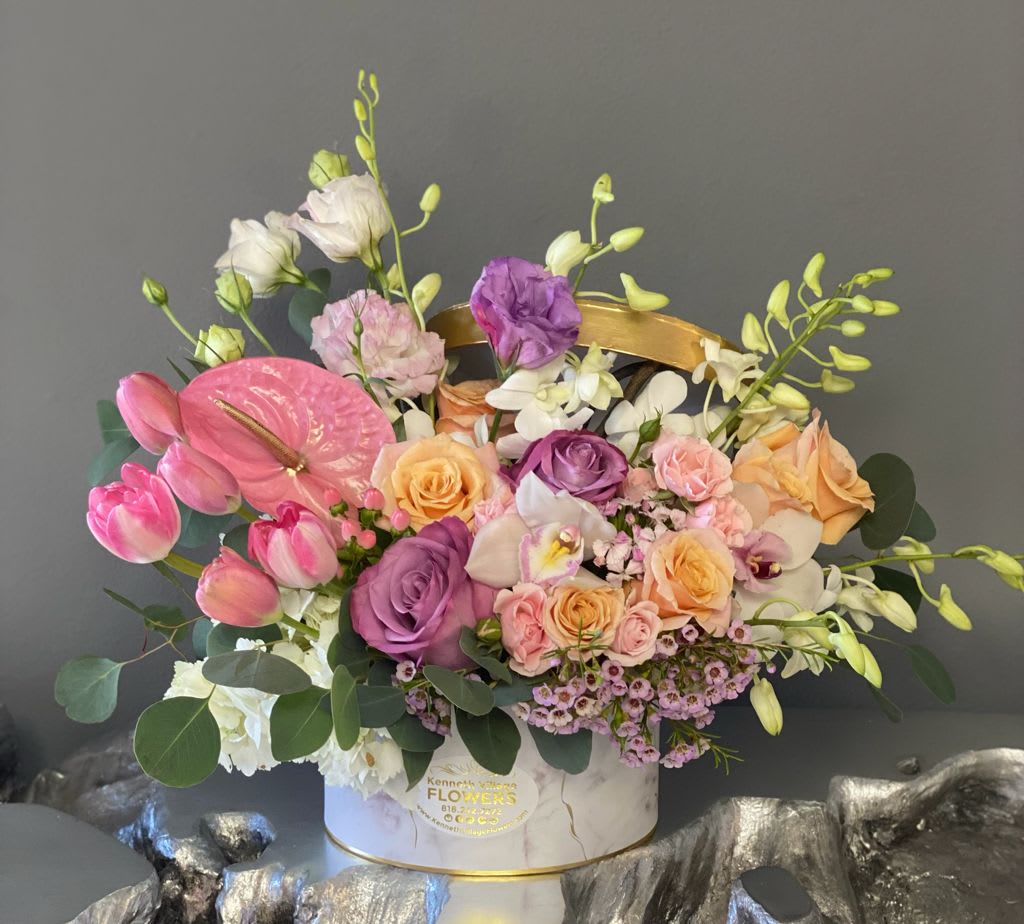 Mixed bouquet with pink tulips, roses, orchids, and anthurium in a white hatbox