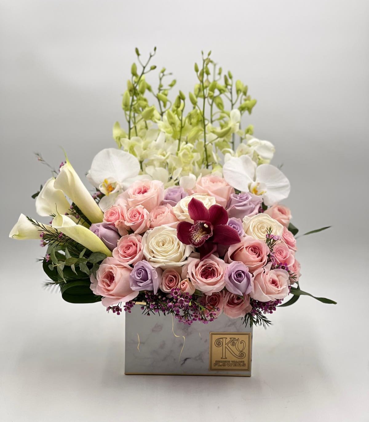 Pink and lavender roses with white orchids in a square box
